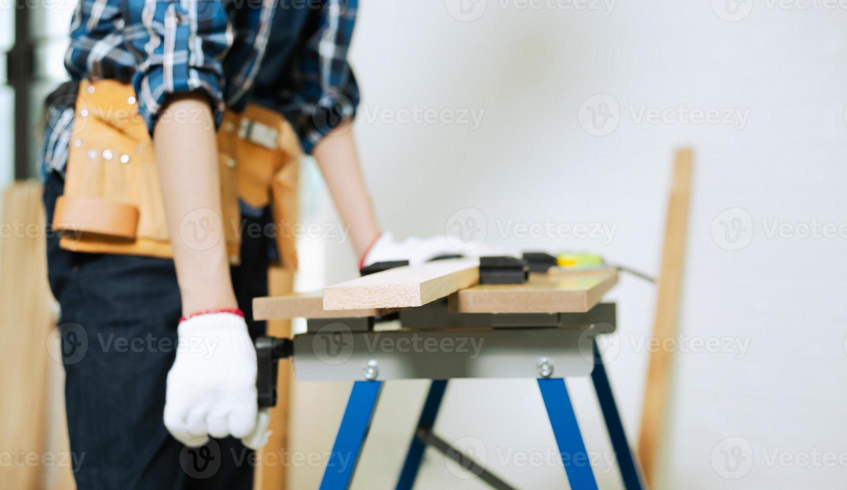 giovane falegname che lavora sulla lavorazione del legno in officina di falegnameria, falegname lavora il legno sul banco di lavoro foto