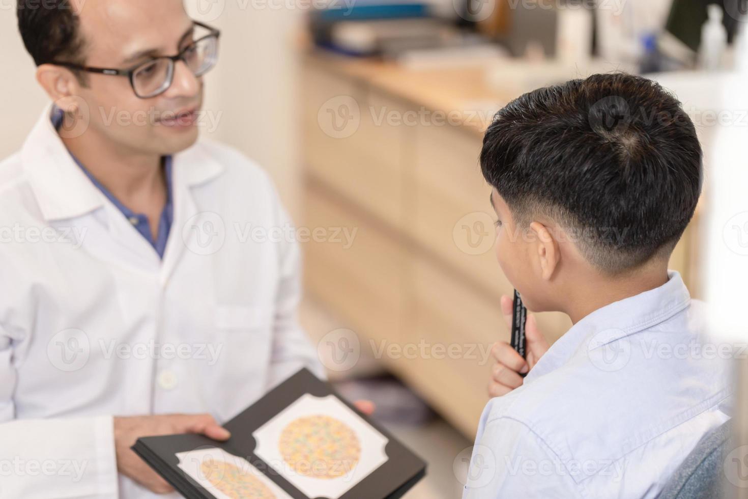 optometrista che esegue il test di percezione della malattia dal daltonismo nel negozio di ottica, ragazzo che fa il test della vista che controlla l'esame con l'ottico optometrista nel negozio di ottica foto