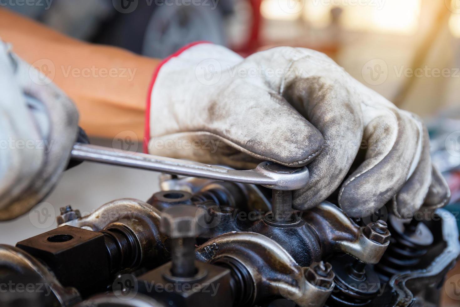 meccanico automatico che regola il motore dell'auto con chiave, servizio di riparazione automobilistica in officina foto