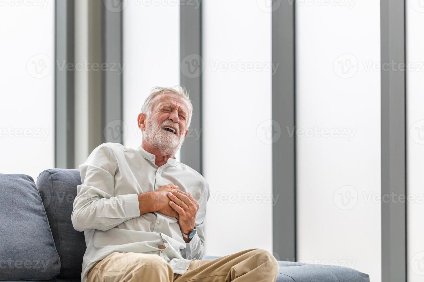 l'uomo maturo preme la mano sul petto ha un attacco di cuore soffre di un dolore insopportabile, l'uomo anziano con dolore al cuore in soggiorno foto