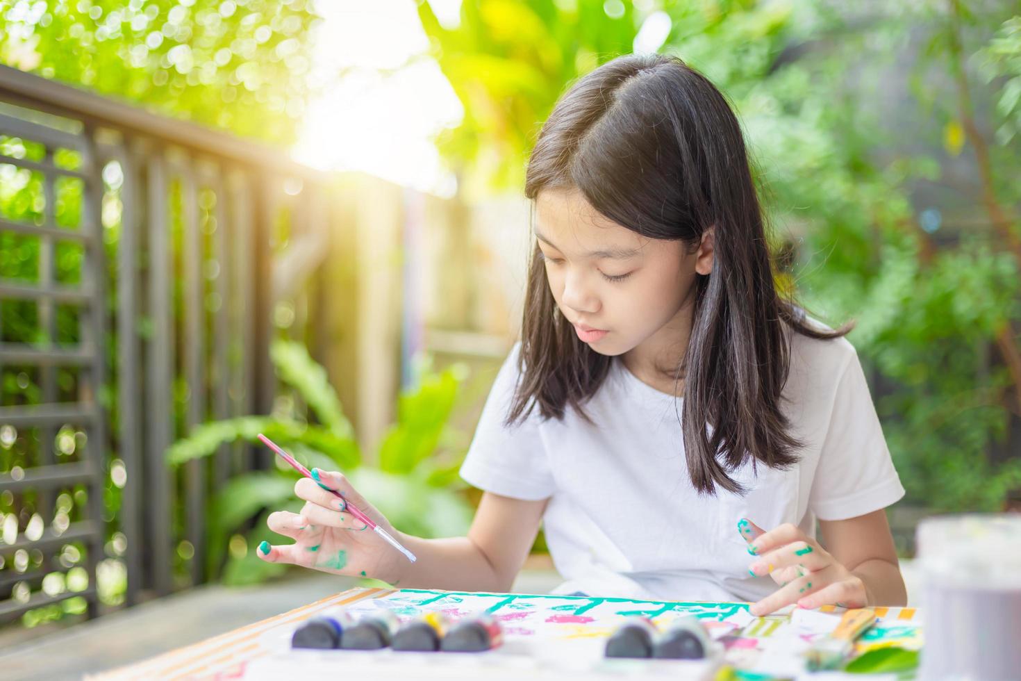 allegra bambina carina che gioca e impara colorando i colori, bambino al tavolo disegna con acquarello, apprendimento e istruzione a casa foto