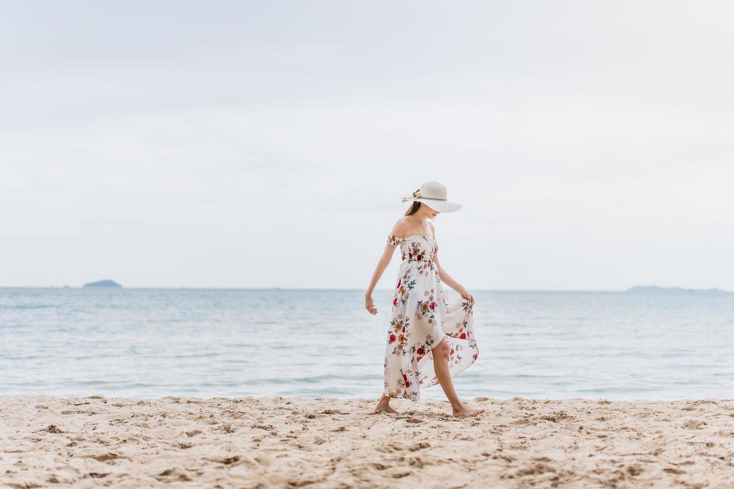 la giovane donna asiatica cammina sulla spiaggia foto