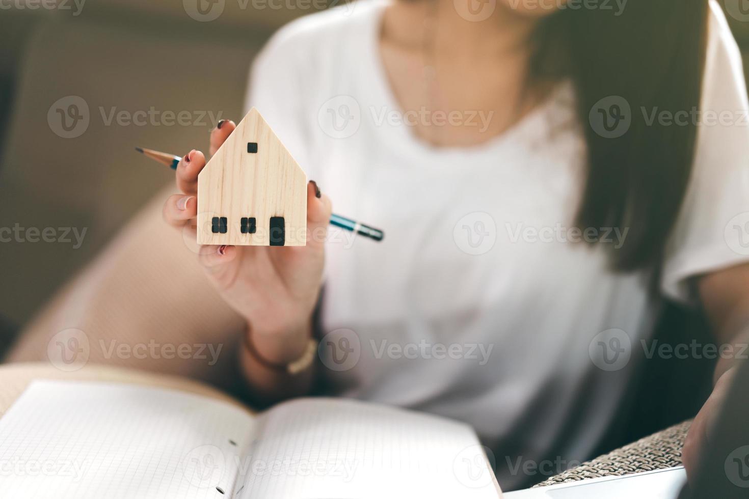 studente asiatico donna mano azienda modello di casa in legno. foto