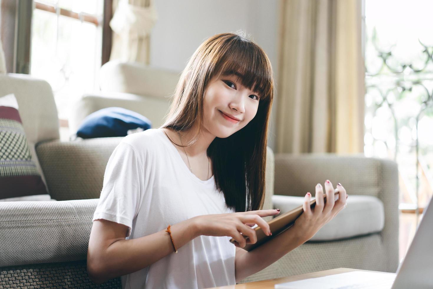 la giovane donna asiatica adulta studia la lezione online a casa tramite internet utilizzando tablet e laptop foto