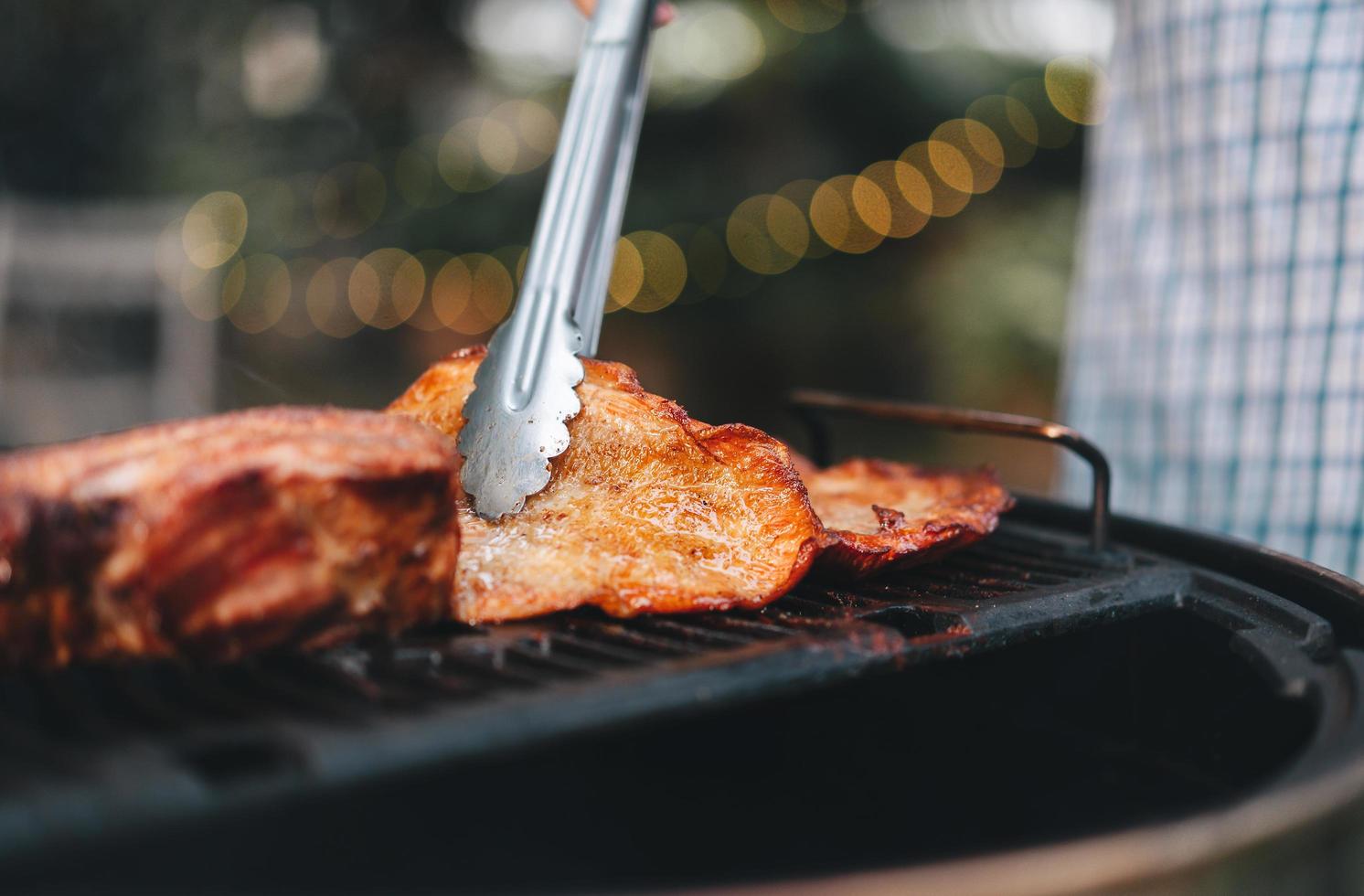 man mano che griglia barbecue in fiamme nel cortile di casa il giorno foto