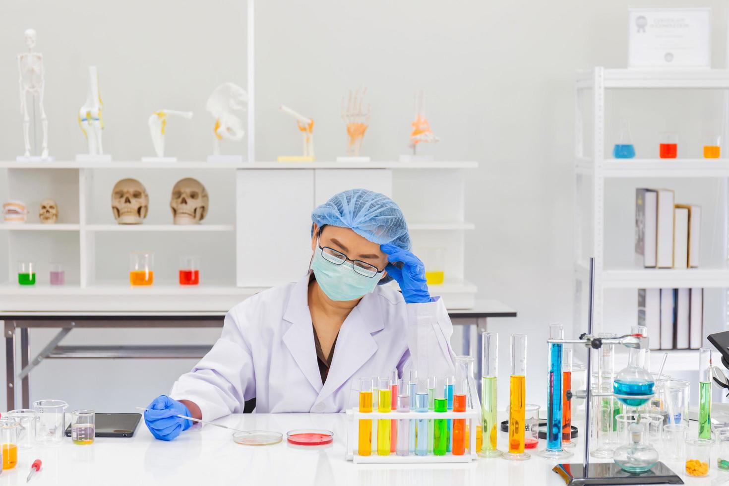 una scienziata asiatica sta ricercando una formula chimica in un laboratorio. foto