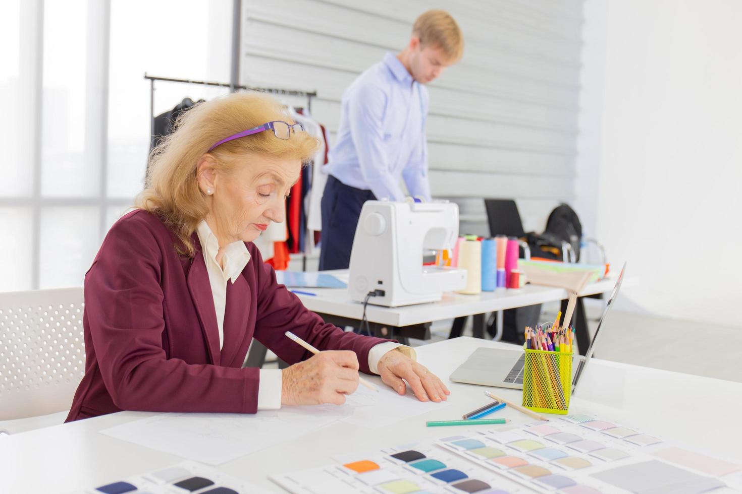 designer donne professioniste stanno disegnando schizzi su carta con le matite in una stanza da cucito. foto