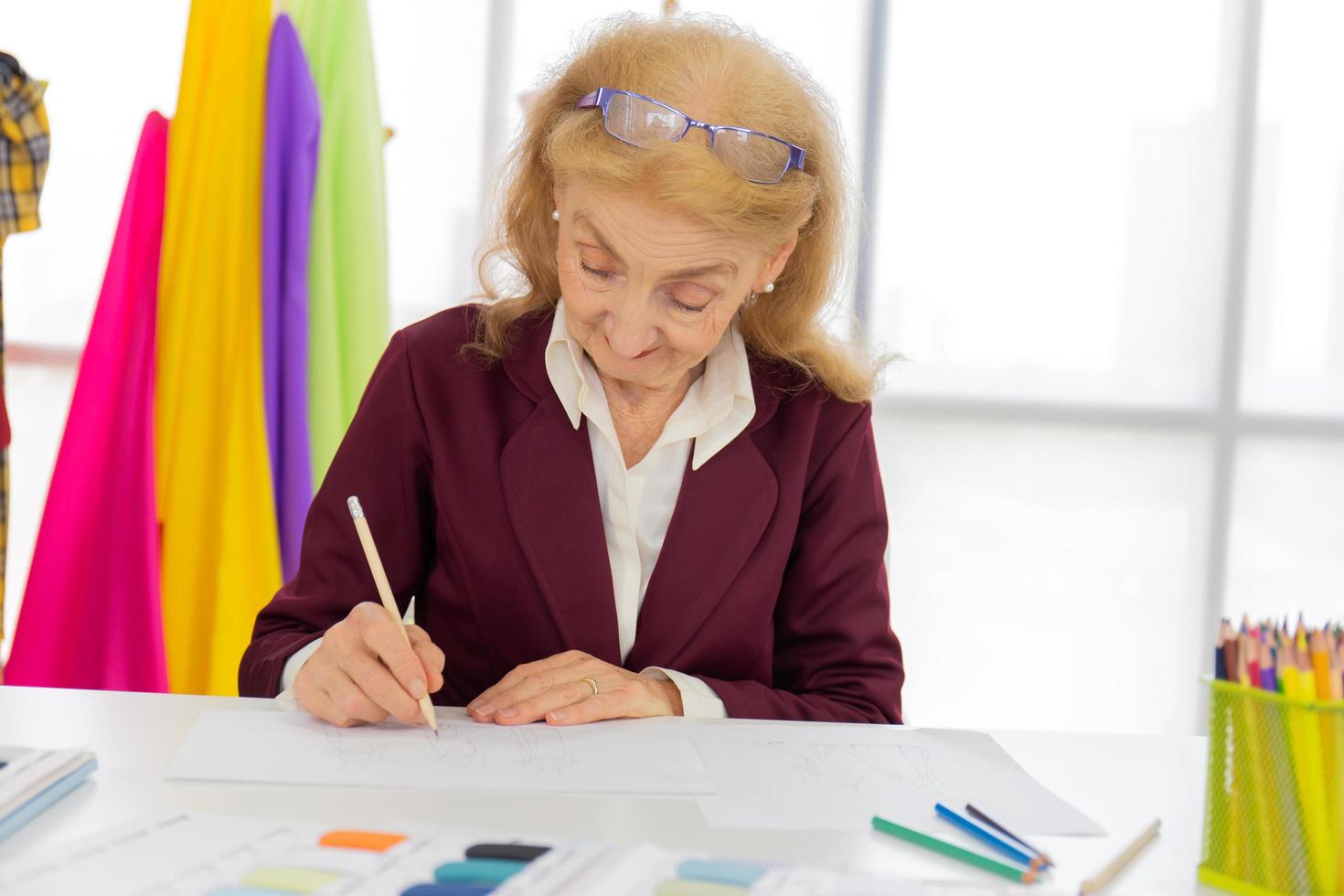 designer donne professioniste stanno disegnando schizzi su carta con le matite in una stanza da cucito. foto