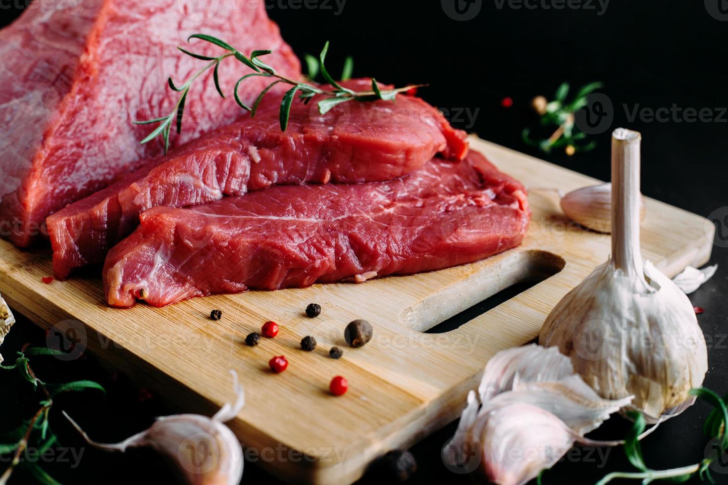 carne fresca e cruda. pezzo intero di manzo rosso pronto da cuocere alla griglia o al barbecue. lavagna nera di sfondo. foto