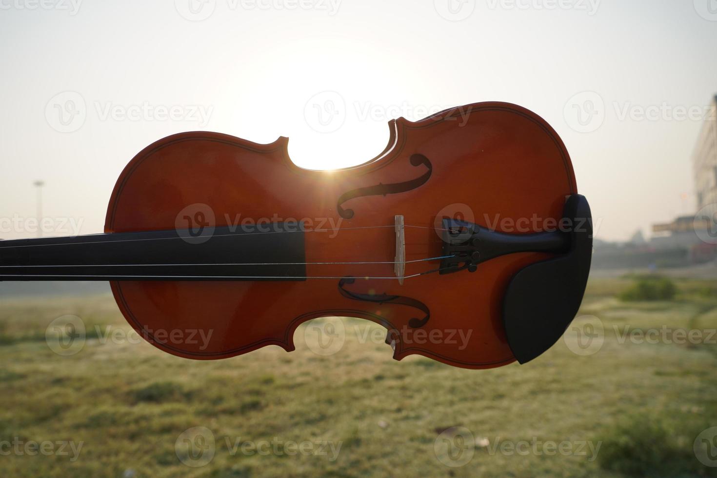 primo piano del violino in mano con effetto luce solare foto