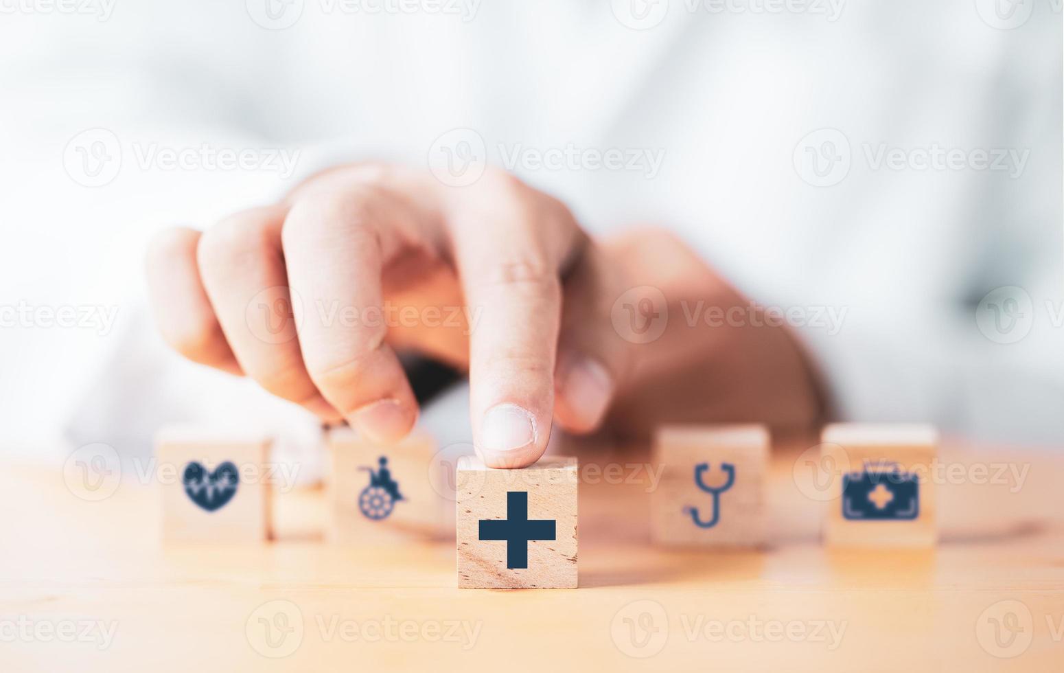 medico che spinge il cubo di blocchi di legno che stampa lo schermo sanitario e le icone mediche per il concetto di salute e benessere. foto