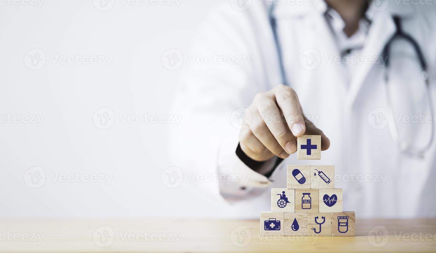 medico che mette e impila il cubo di blocchi di legno che stampa lo schermo sanitario e le icone mediche per il concetto di salute e benessere. foto