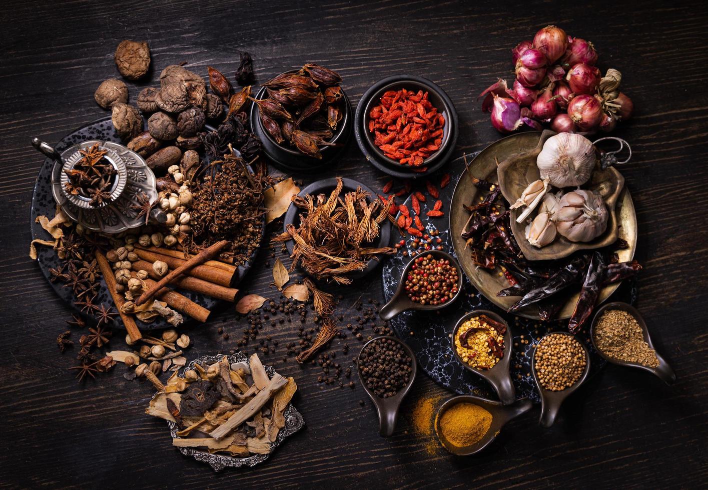 cibo nativo tailandese, spezie erbe e vari ingredienti presi dall'angolo di vista superiore. gruppo di verdure secche calde e piccanti, noci e cereali per preparare cibo asiatico su fondo di legno. foto in tono scuro