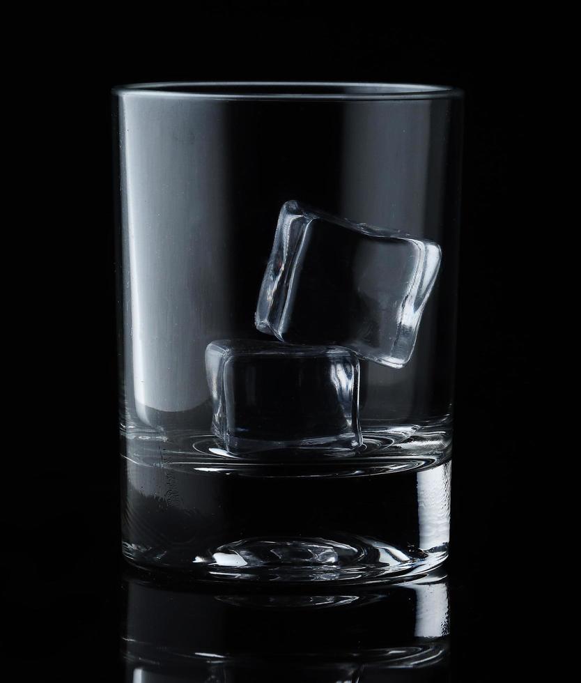 cubetti di ghiaccio in vetro vuoto su sfondo nero. bicchiere d'acqua o whisky e vino. bicchiere vuoto per bevande alcoliche foto