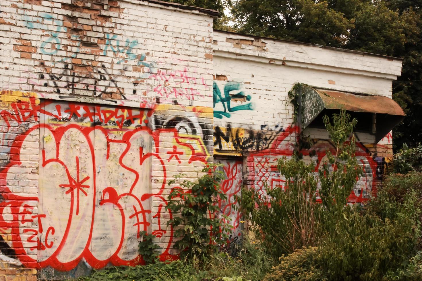 vecchio muro di mattoni bianchi con graffiti e vecchia tenda da sole tra gli alberi in ucraina kyiv foto