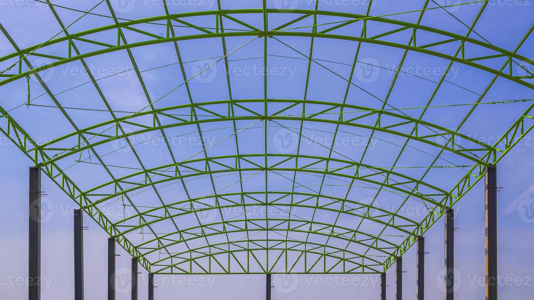 vista ad angolo basso della struttura del tetto in metallo verde di un edificio industriale contro il cielo blu in cantiere foto