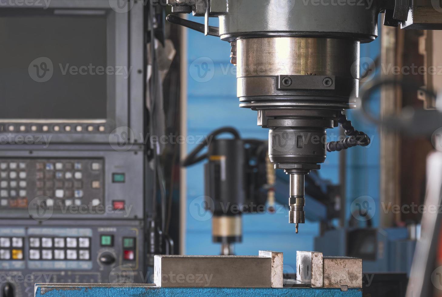 primo piano della fresatrice cnc utensile con mulino nel mandrino che si prepara a lavorare i dettagli metallici nell'area dell'officina di produzione foto