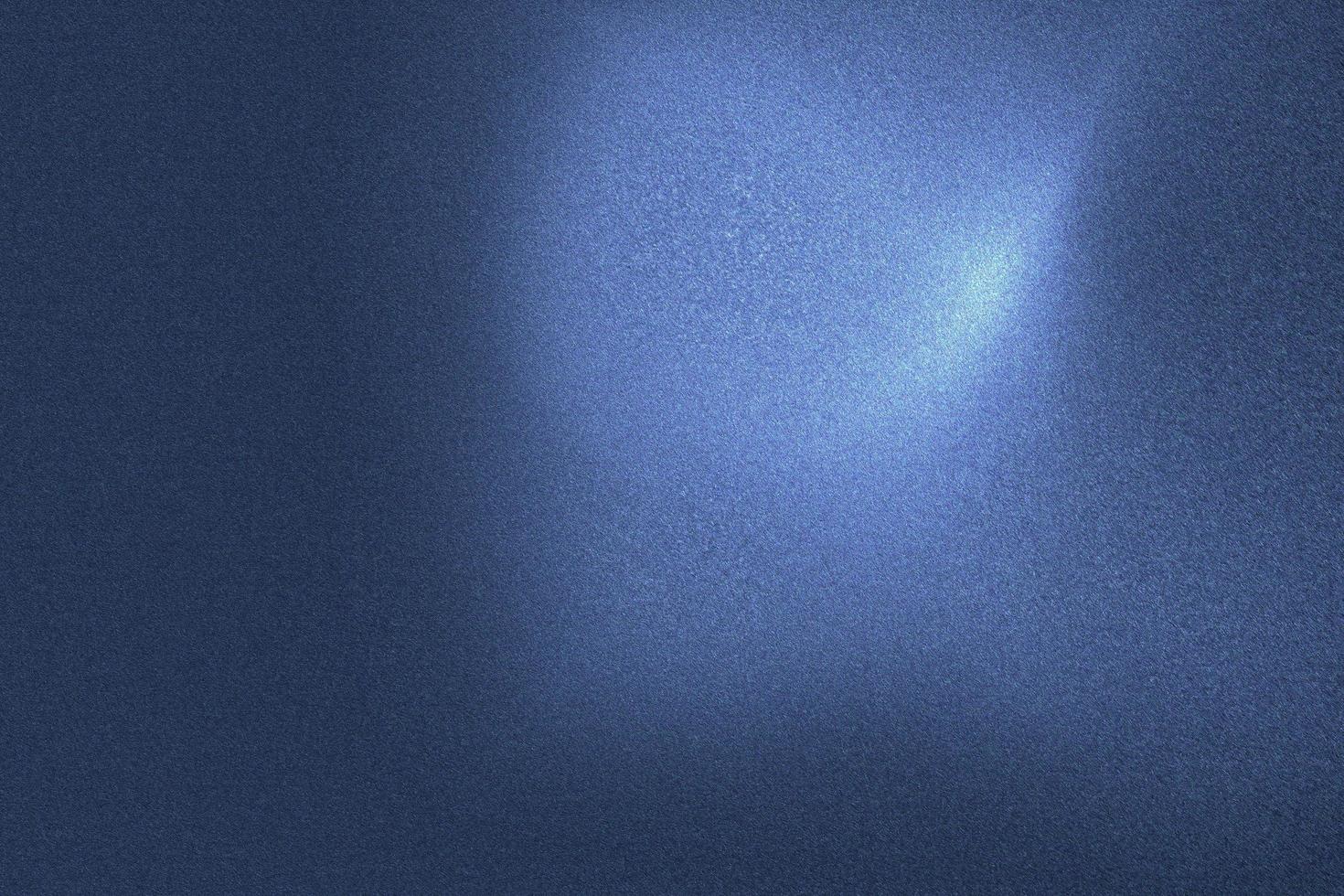 luce che brilla sulla parete metallica dell'onda blu nella stanza buia, fondo astratto della struttura foto