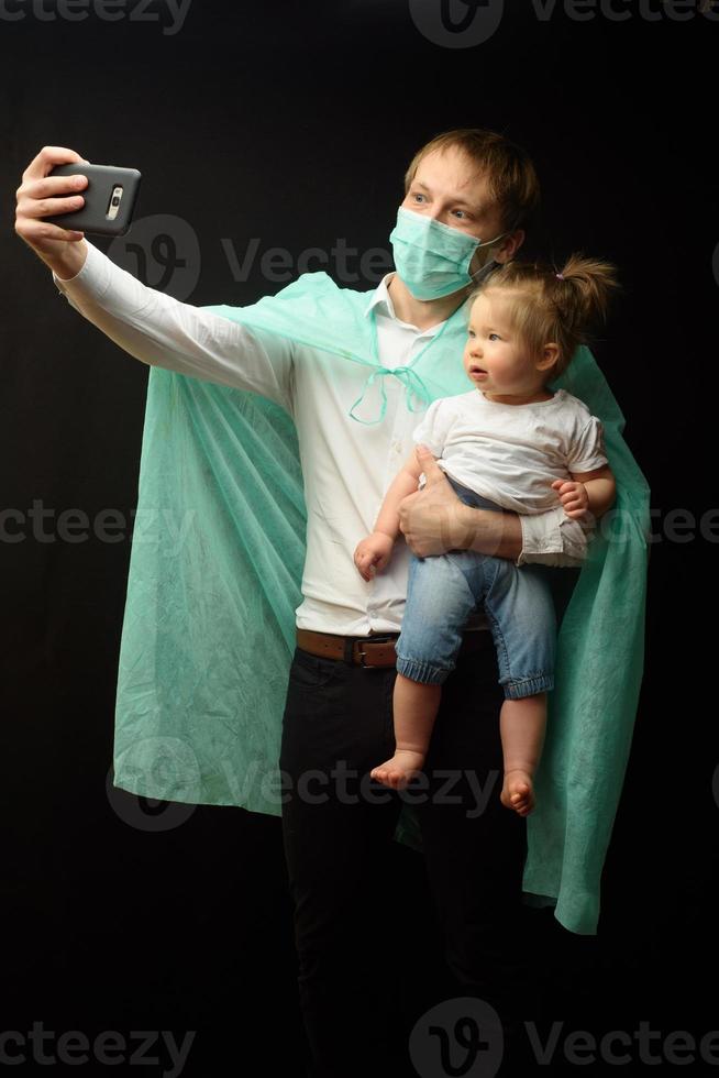 il padre con una maschera medica tiene la sua piccola figlia. il concetto di protezione dei bambini durante l'epidemia di coronavirus foto
