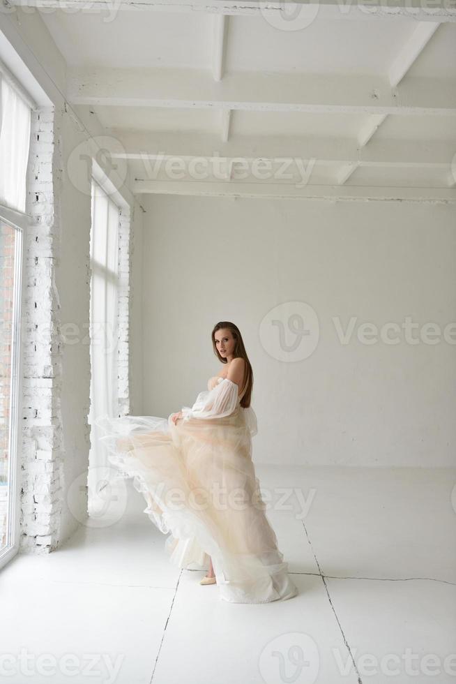 ritratto di una bella sposa in piena crescita in studio su sfondo bianco. la donna sta con le spalle e guarda nell'inquadratura. foto