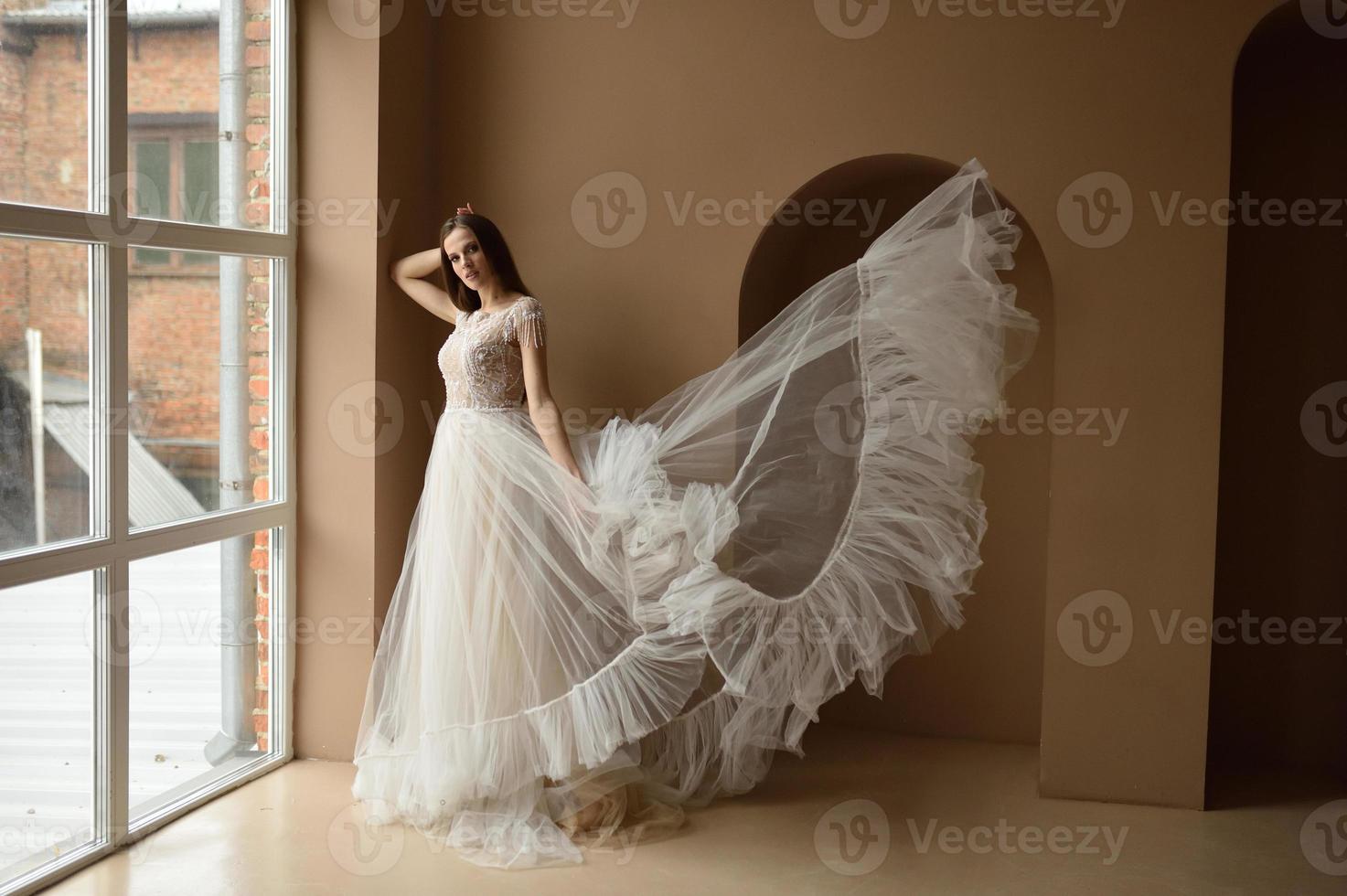 ritratto di una bella sposa in piena crescita in studio su sfondo bianco. la donna sta con le spalle e guarda nell'inquadratura. foto