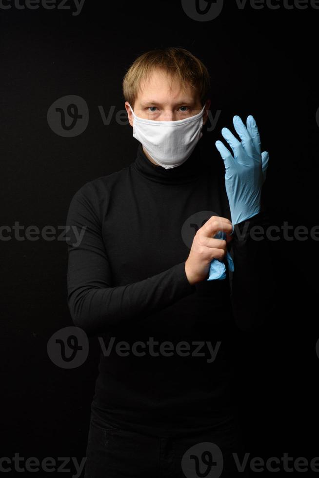 uomo che indossa guanti protettivi in lattice e maschera facciale. vista frontale del viso dell'uomo che indossa una maschera medica. coronavirus covid-19 e concetto di assistenza sanitaria foto