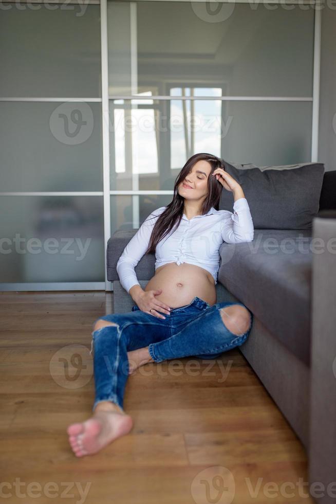 un uomo e una donna incinta sono seduti abbracciati sul divano. foto