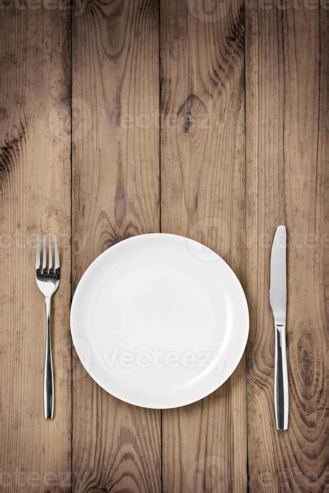messa in tavola, piatto, cucchiaio e forchetta sulla tavola di legno. foto