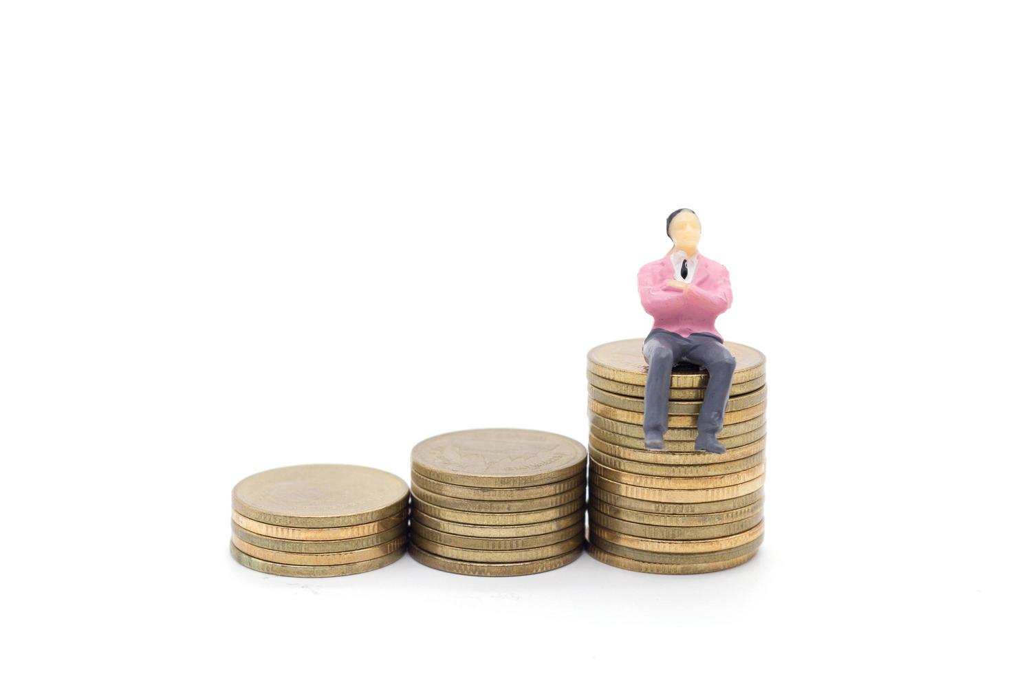 uomo d'affari in miniatura e monete su sfondo bianco foto