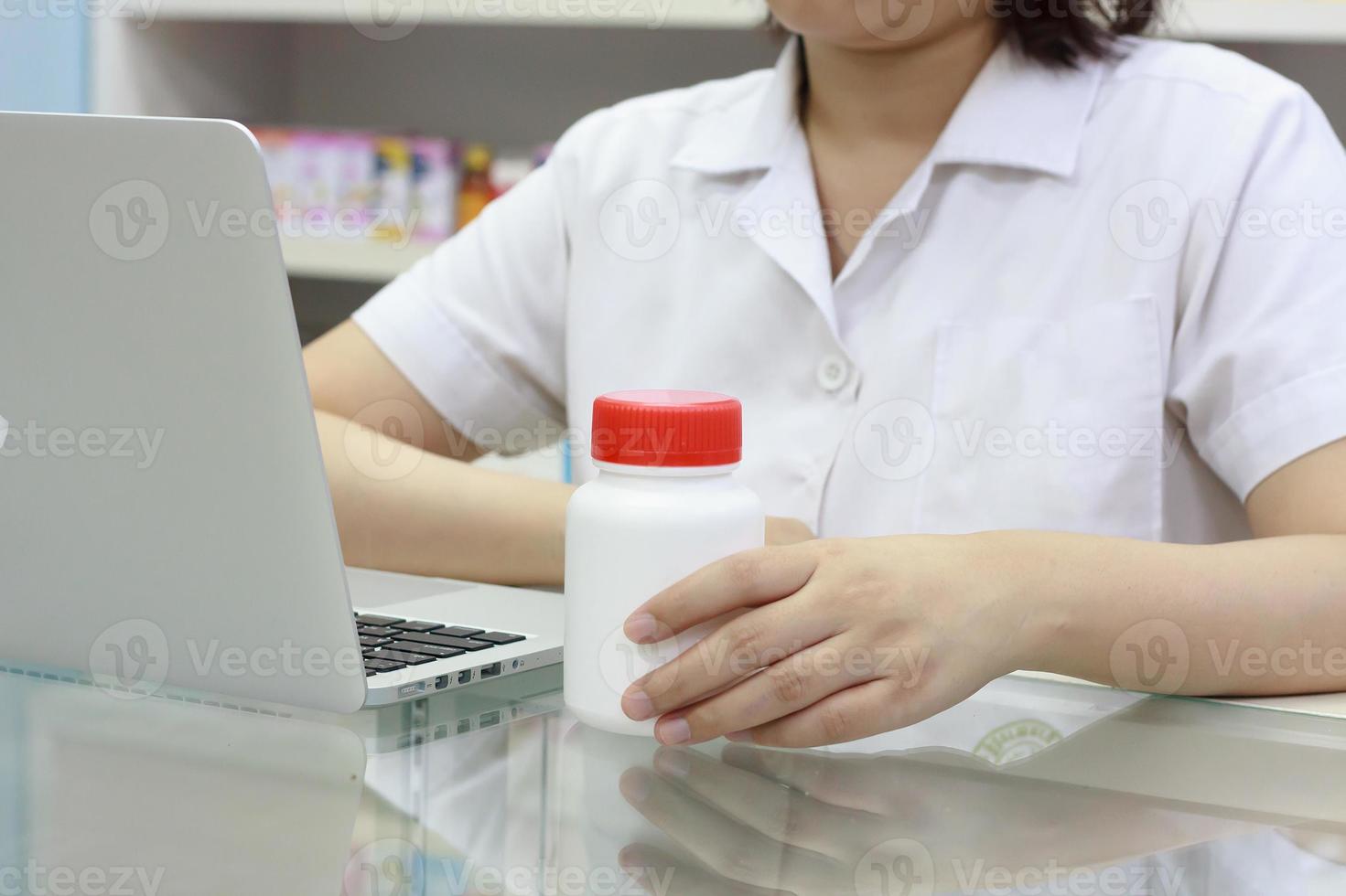 farmacista con computer portatile e farmaci in farmacia foto