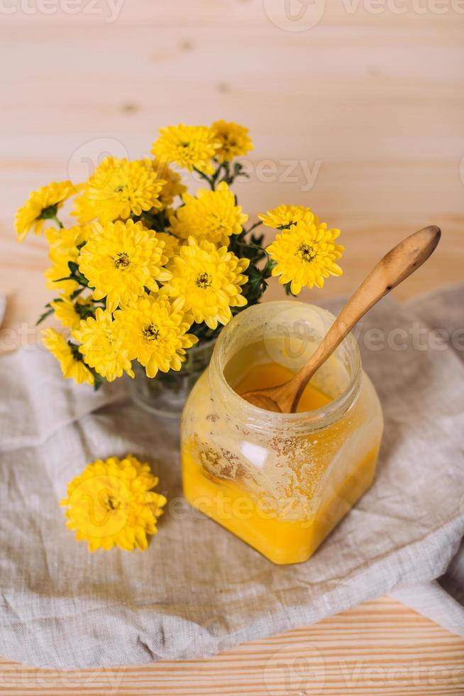 un barattolo di miele solido e fiori su fondo di legno. foto