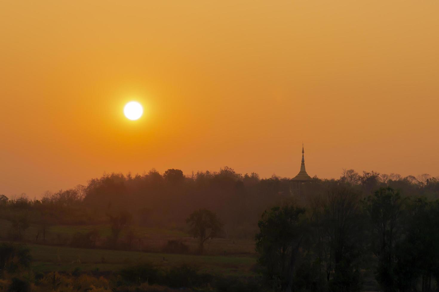 sole, tramonto, calda luce arancione, c'è una pagoda accanto. foto