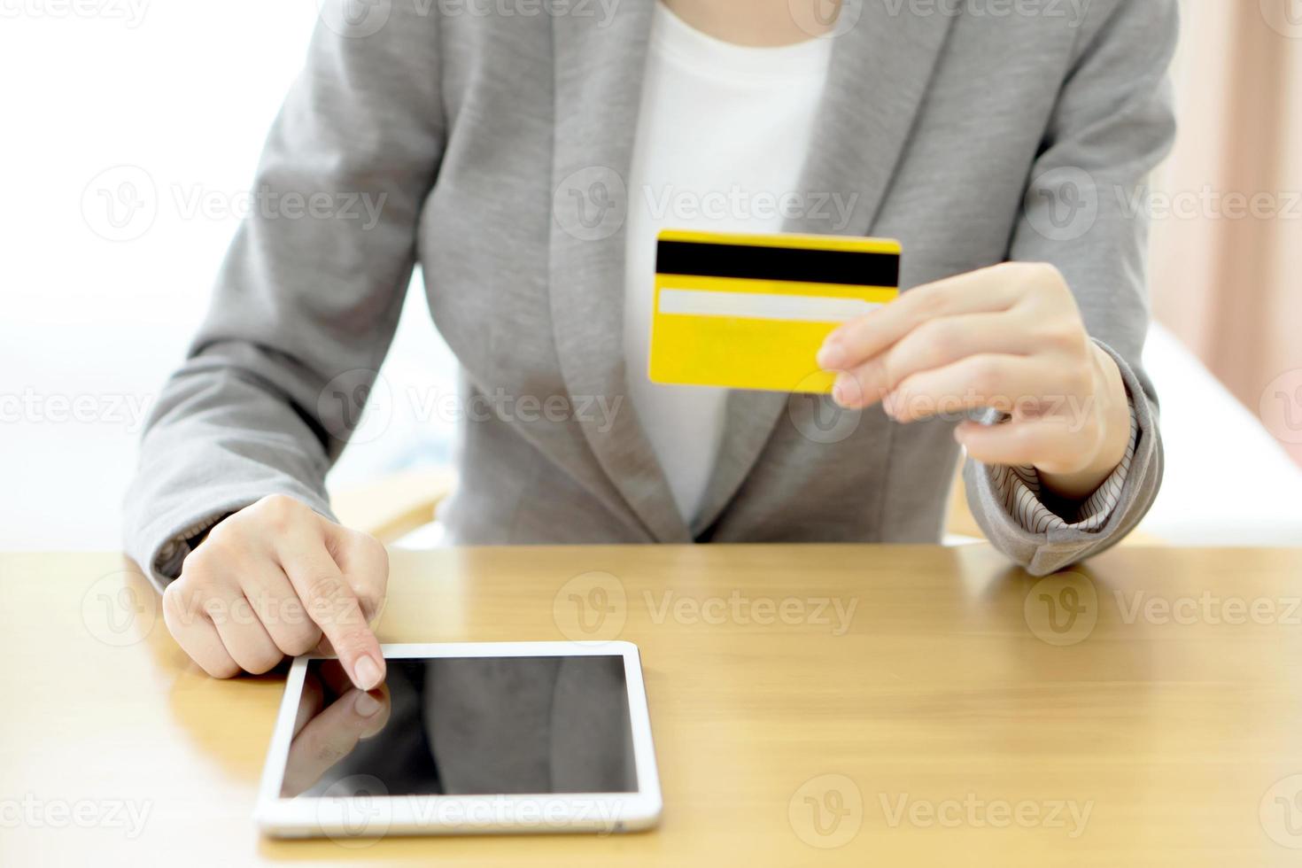 le mani della donna del primo piano in possesso di una carta di credito e utilizzando tablet pc foto