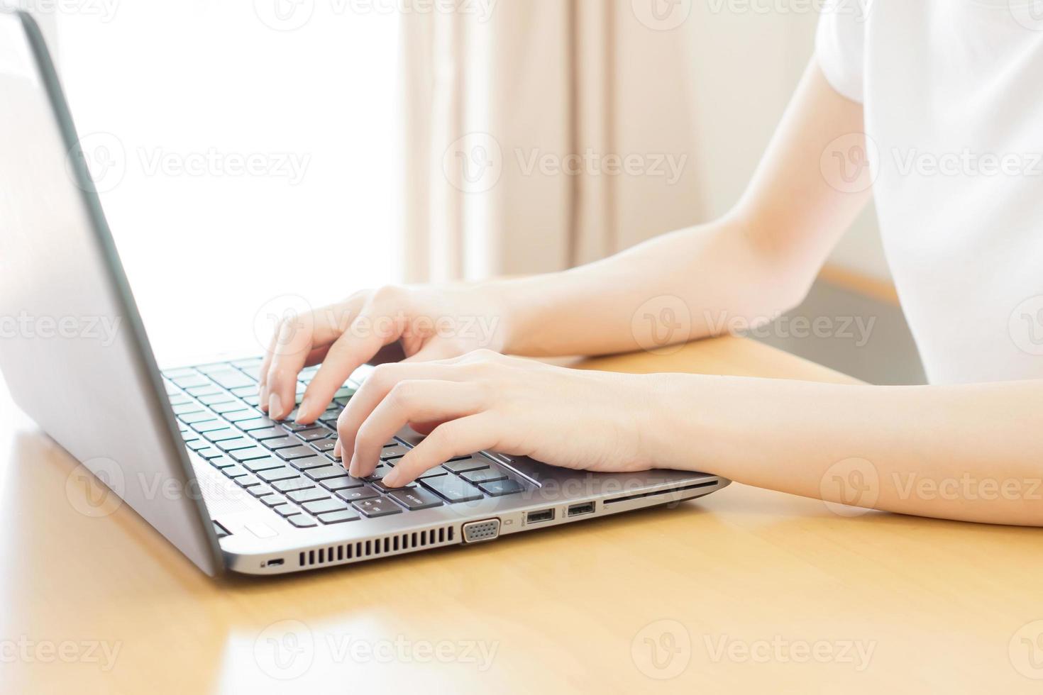 retrovisione delle mani della donna di affari occupate usando il computer portatile alla scrivania dell'ufficio, con copyspace foto