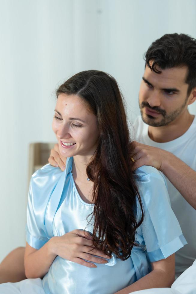 marito fa un massaggio alla moglie incinta in modo che la moglie possa rilassarsi e avere un buon umore foto