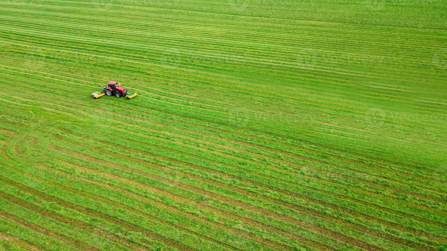 il trattore falcia l'erba vista dall'alto dal drone foto