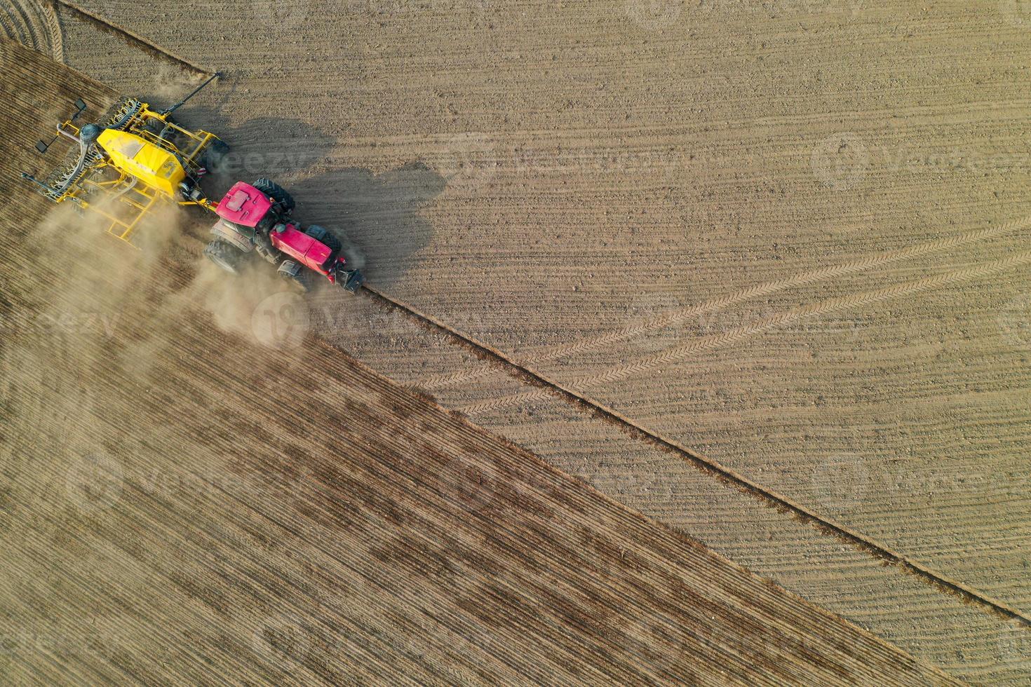 drone pov del trattore che semina mais in campo, vista aerea dell'attività agricola foto