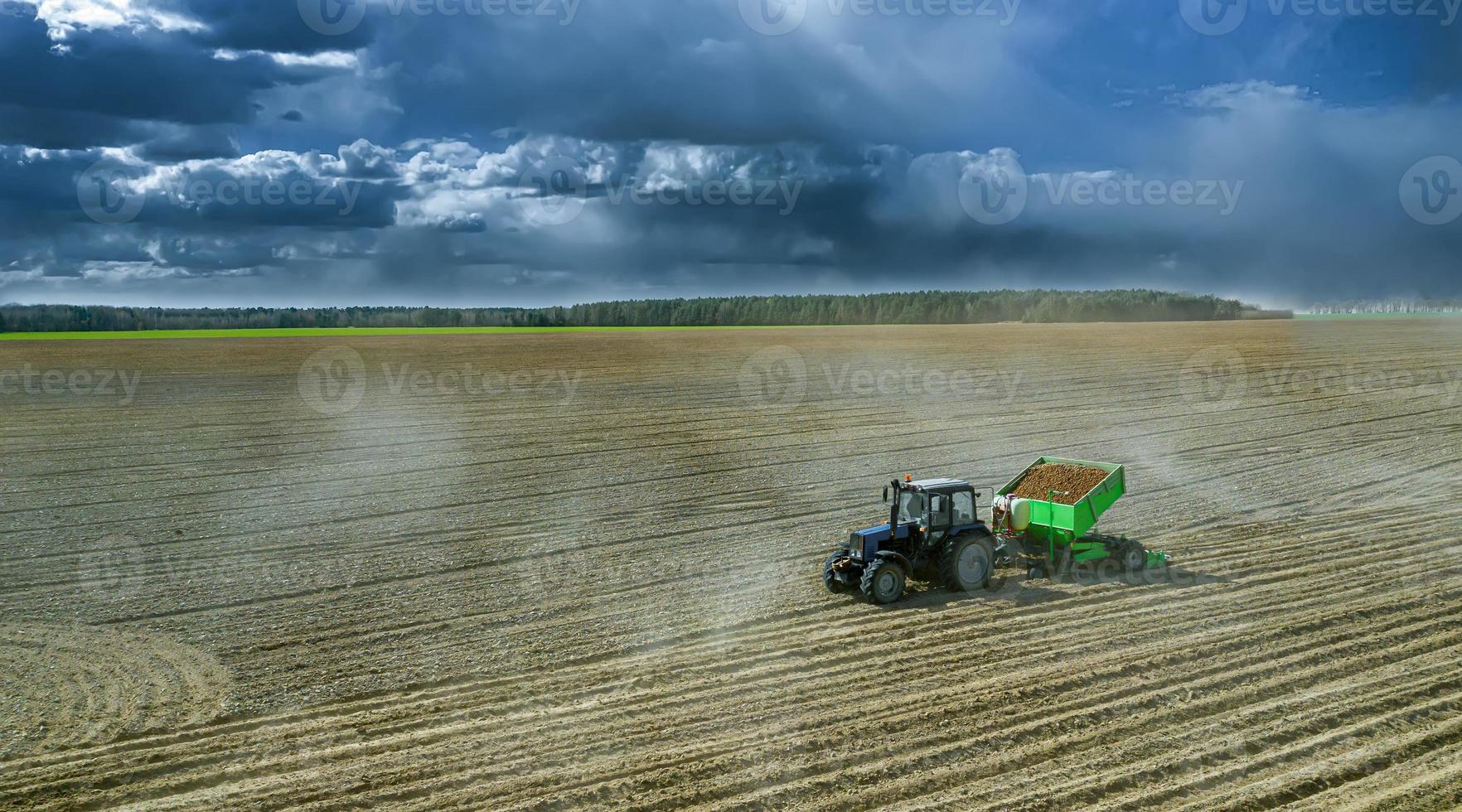 trattori al lavoro in un campo che coltivano il terreno pronto per la semina delle patate. vista aerea. foto