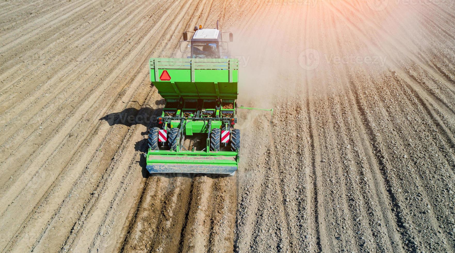 un contadino e un trattore nel campo piantando patate nei fertili campi agricoli. vista aerea. foto