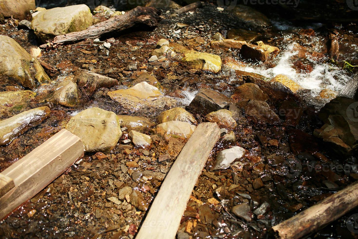 ruscello di montagna che scorre con acqua trasparente e pietre sul fondo foto
