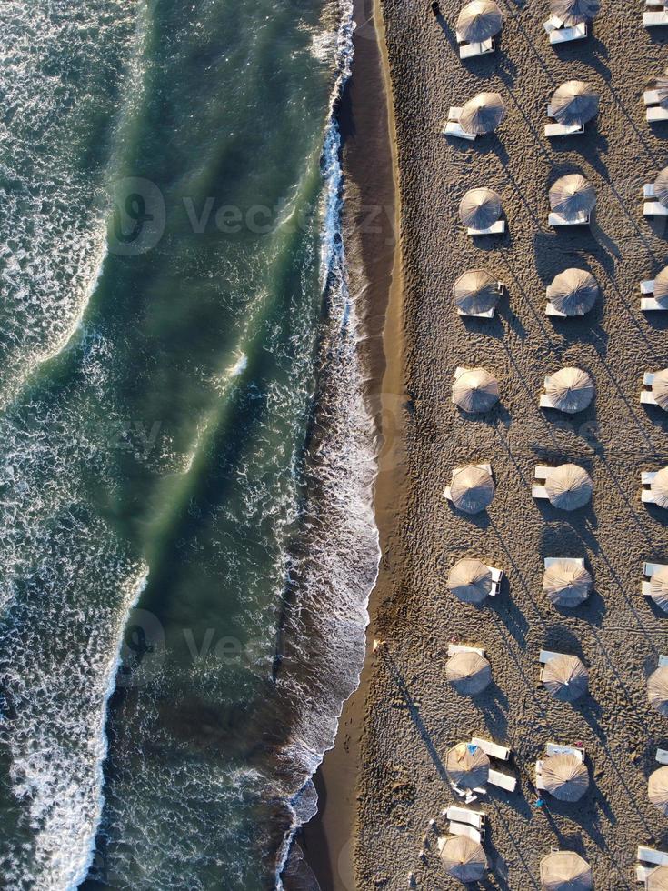 vista dall'alto, splendida vista aerea di un'incredibile spiaggia deserta con ombrelloni bianchi e acque turchesi con onde. foto