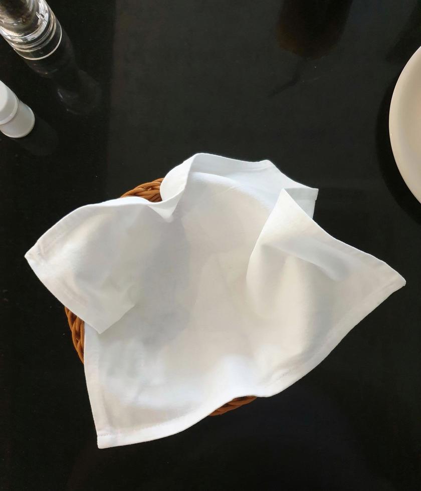 cesto di pane vuoto, con tovagliolo di stoffa bianca. sul tavolo da pranzo nero. foto