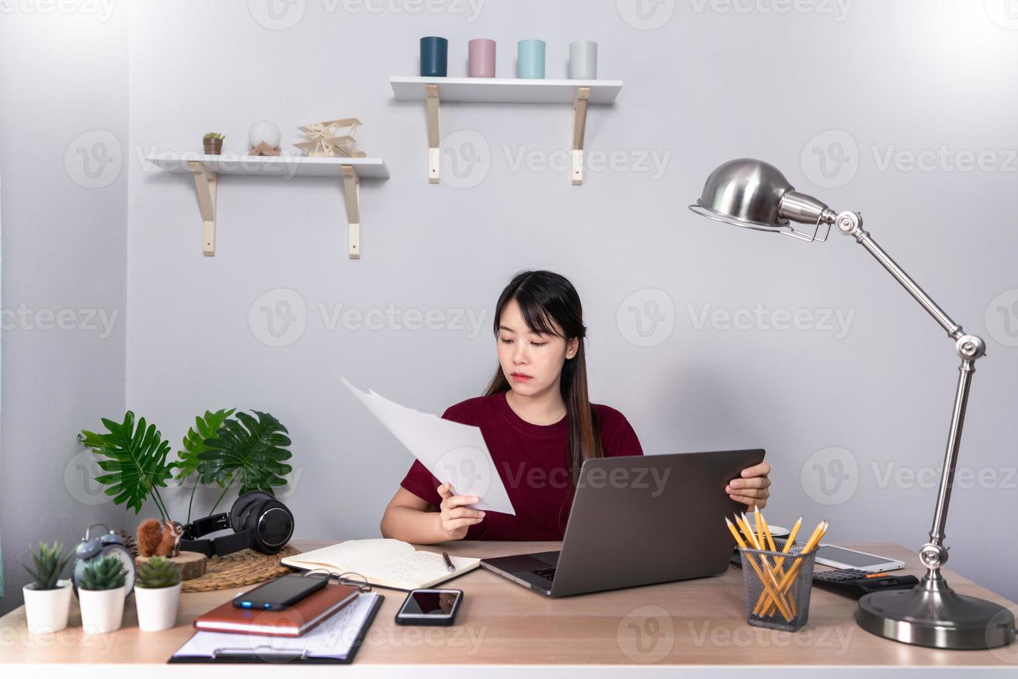 una giovane e bella ragazza asiatica d'affari rilassante usa un laptop che lavora a distanza da casa sulla scrivania come libero professionista, quarantena per coronavirus e concetto di smart working. foto