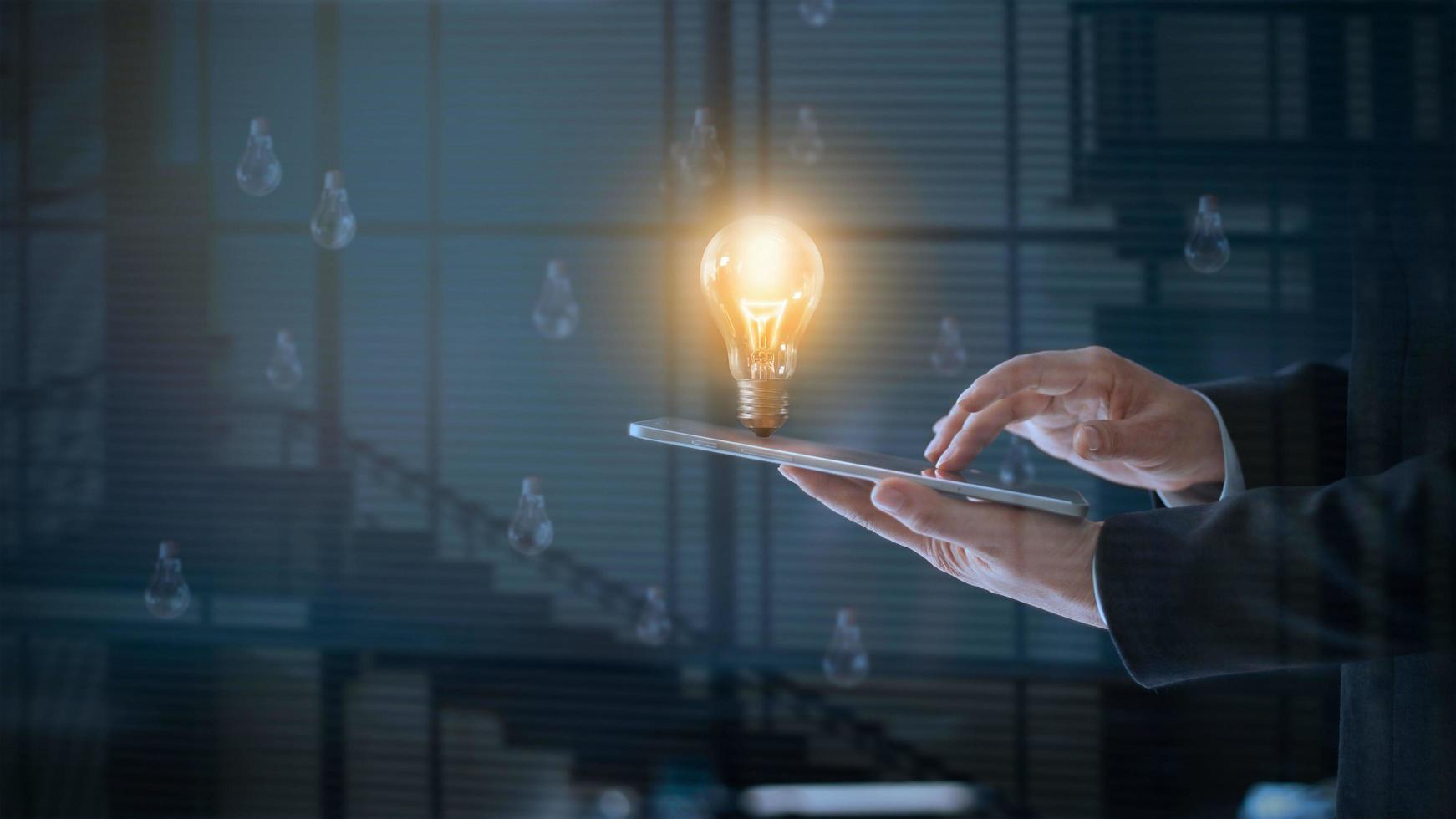 lampadina incandescente sopra il labtop dell'uomo d'affari tra gli altri che non sono luminosi, è il simbolo di un'idea creativa e brillante o di un concetto di leadership, innovazione e creatività foto