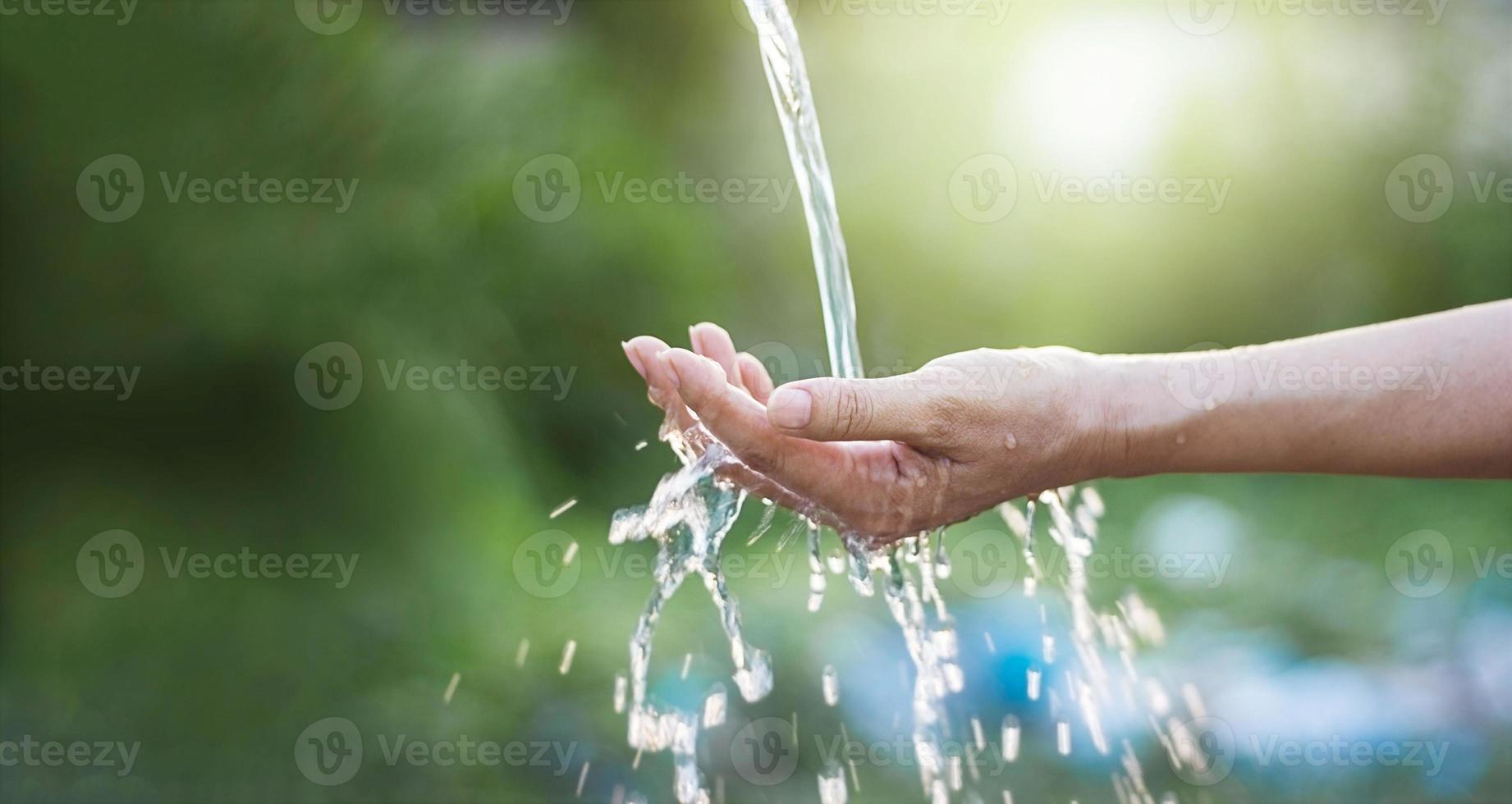 acqua che versa nella mano della donna sullo sfondo della natura, problemi ambientali foto