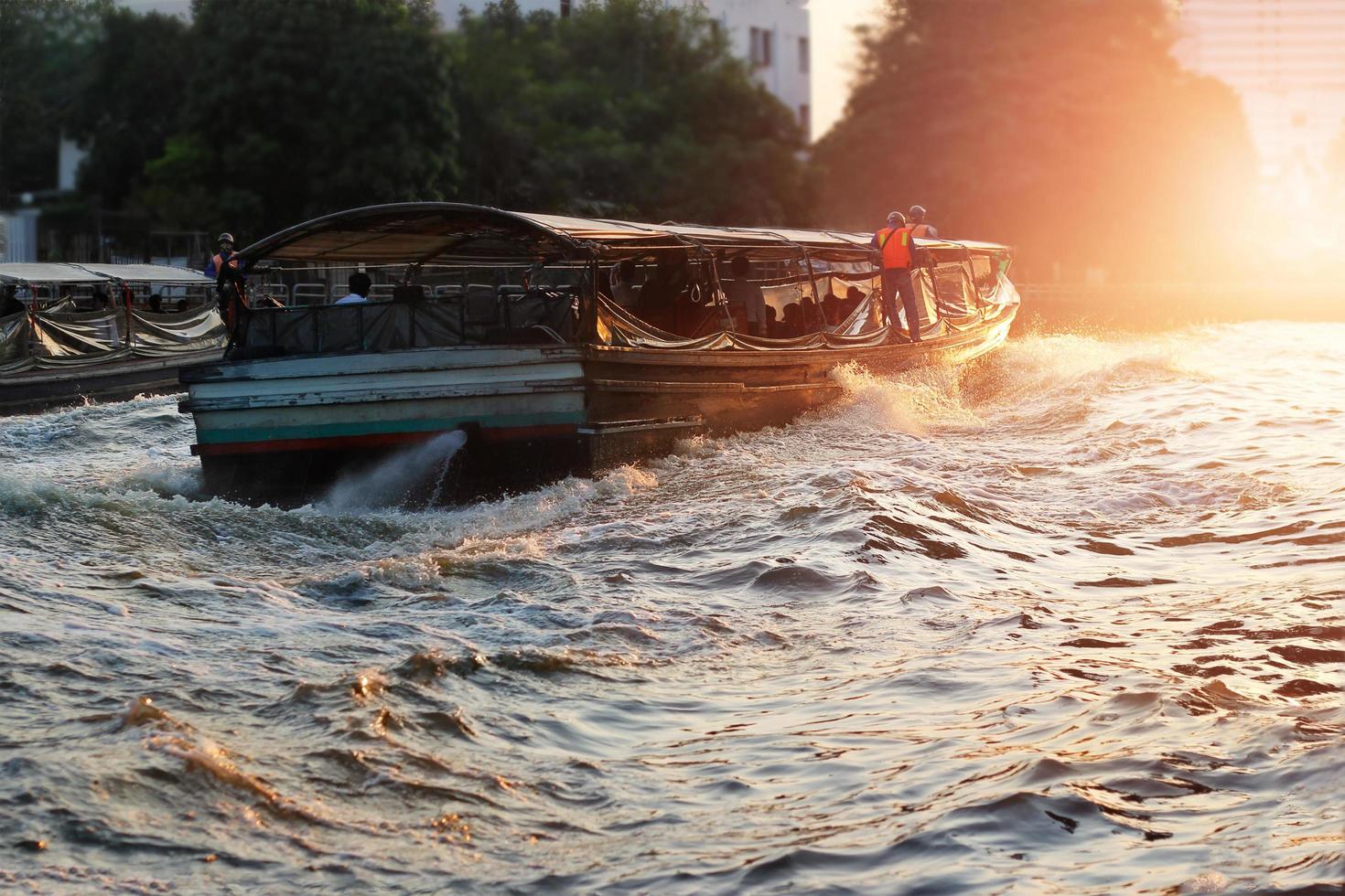 barca da trasporto nella città fluviale su sfondo tramonto, tonalità di colore drammatica foto