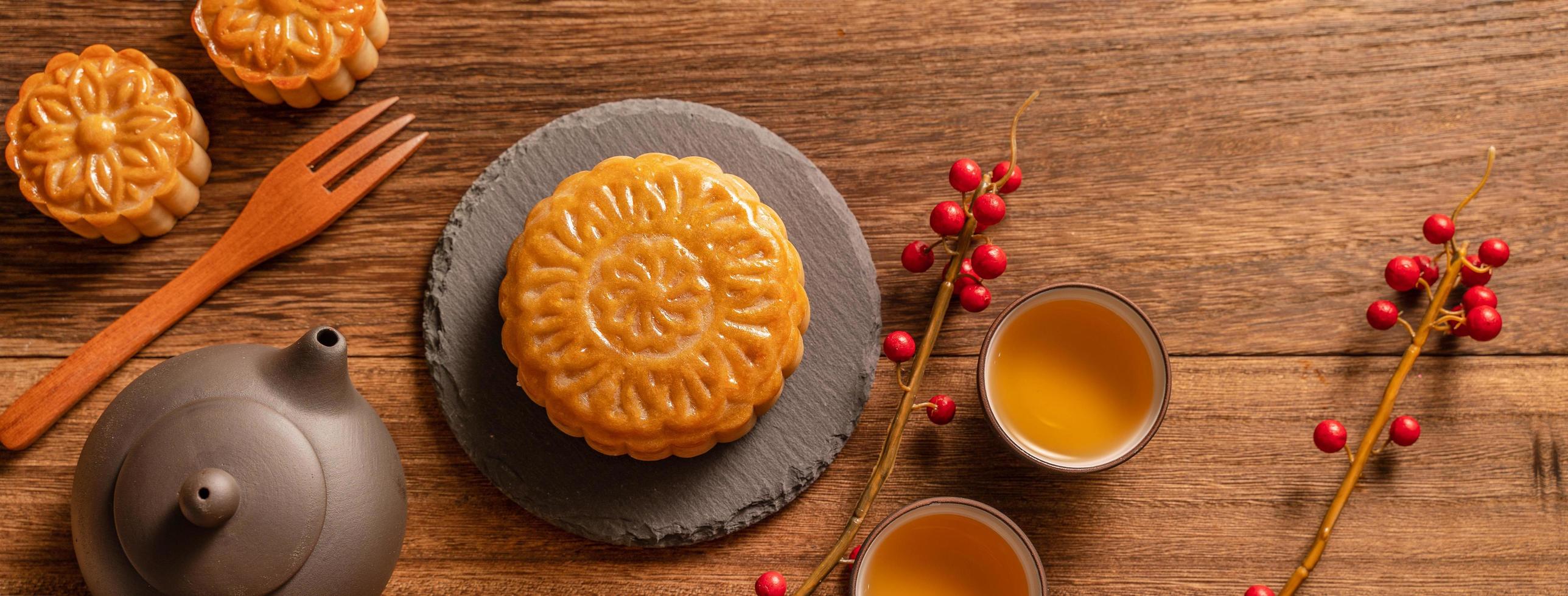 Moon cake mooncake table setting - pasticceria tradizionale cinese con tazze da tè su sfondo di legno, concetto di festival di metà autunno, vista dall'alto, piatto. foto