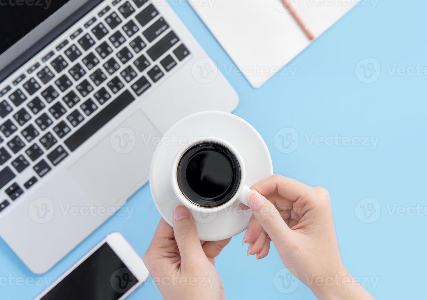 concetto di business, relax nell'orario di lavoro, bere un caffè facendo una pausa su un tavolo da ufficio azzurro pulito, spazio per la copia, disposizione piatta, vista dall'alto, mockup foto