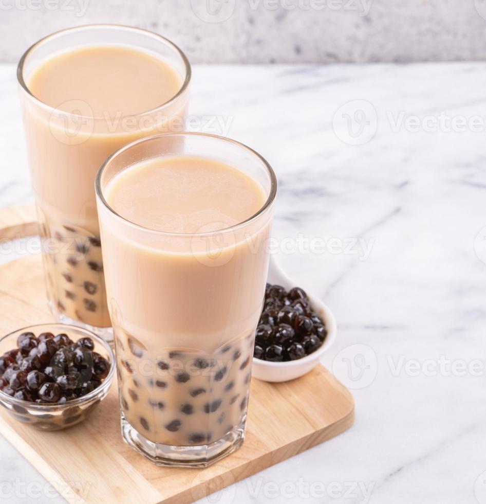 bevanda popolare taiwan - tè al latte con bolle con perla di tapioca palla in bicchiere su marmo bianco tavolo vassoio in legno sfondo, primo piano, spazio di copia foto