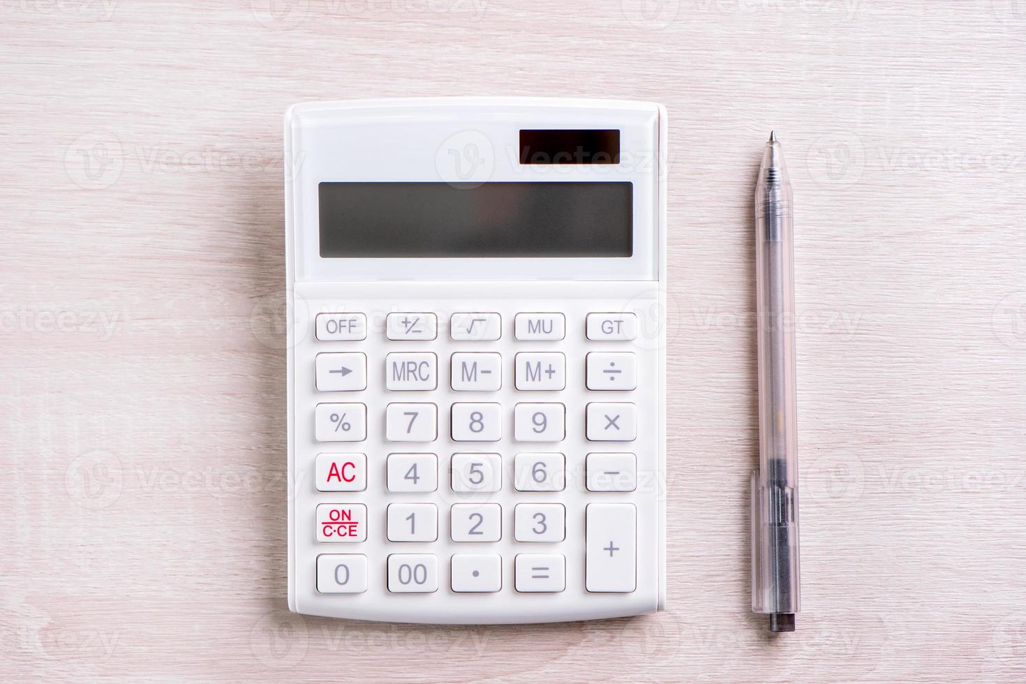 calcolatrice bianca e penna su tavolo di legno luminoso, analisi e statistiche del profitto finanziario, concetto di rischio di investimento, spazio per la copia, vista dall'alto piatto foto